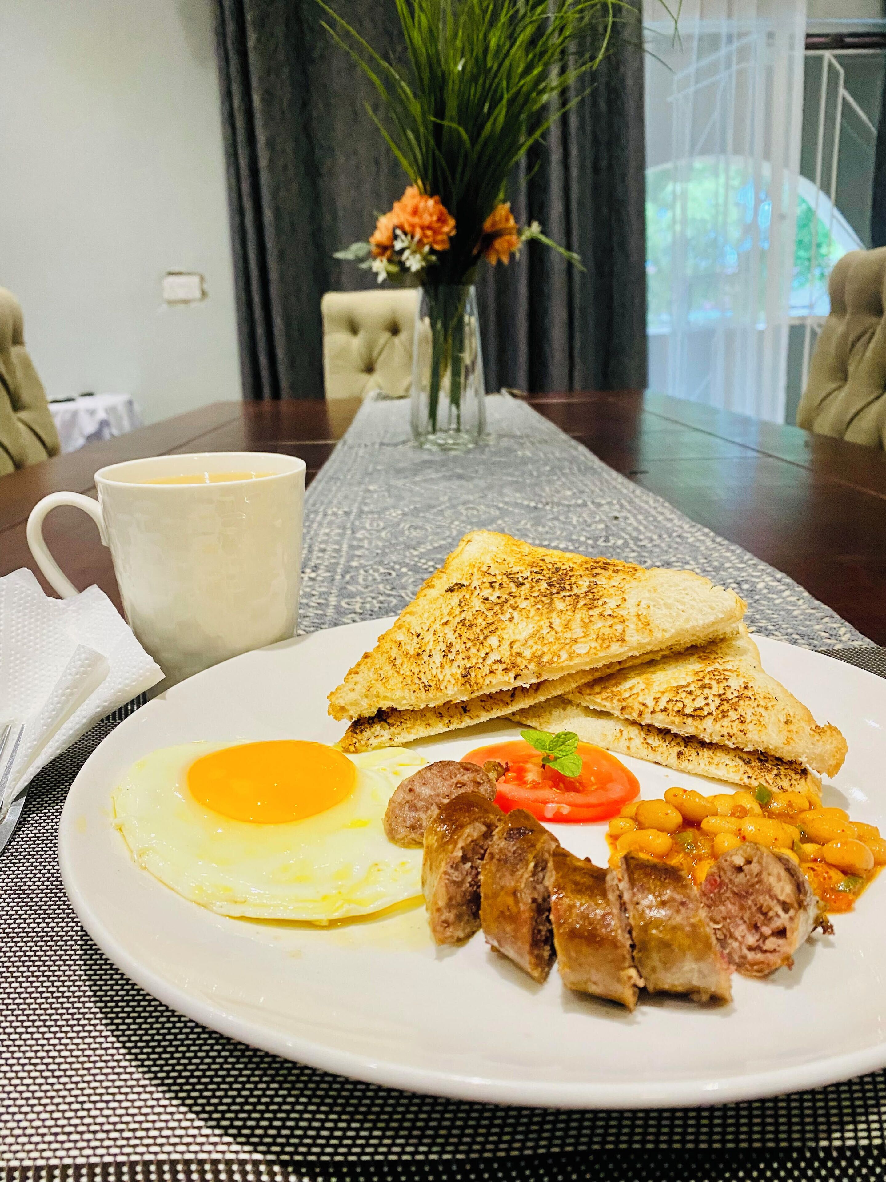 Un plato de desayuno con tostadas, huevos, salchichas y frijoles.