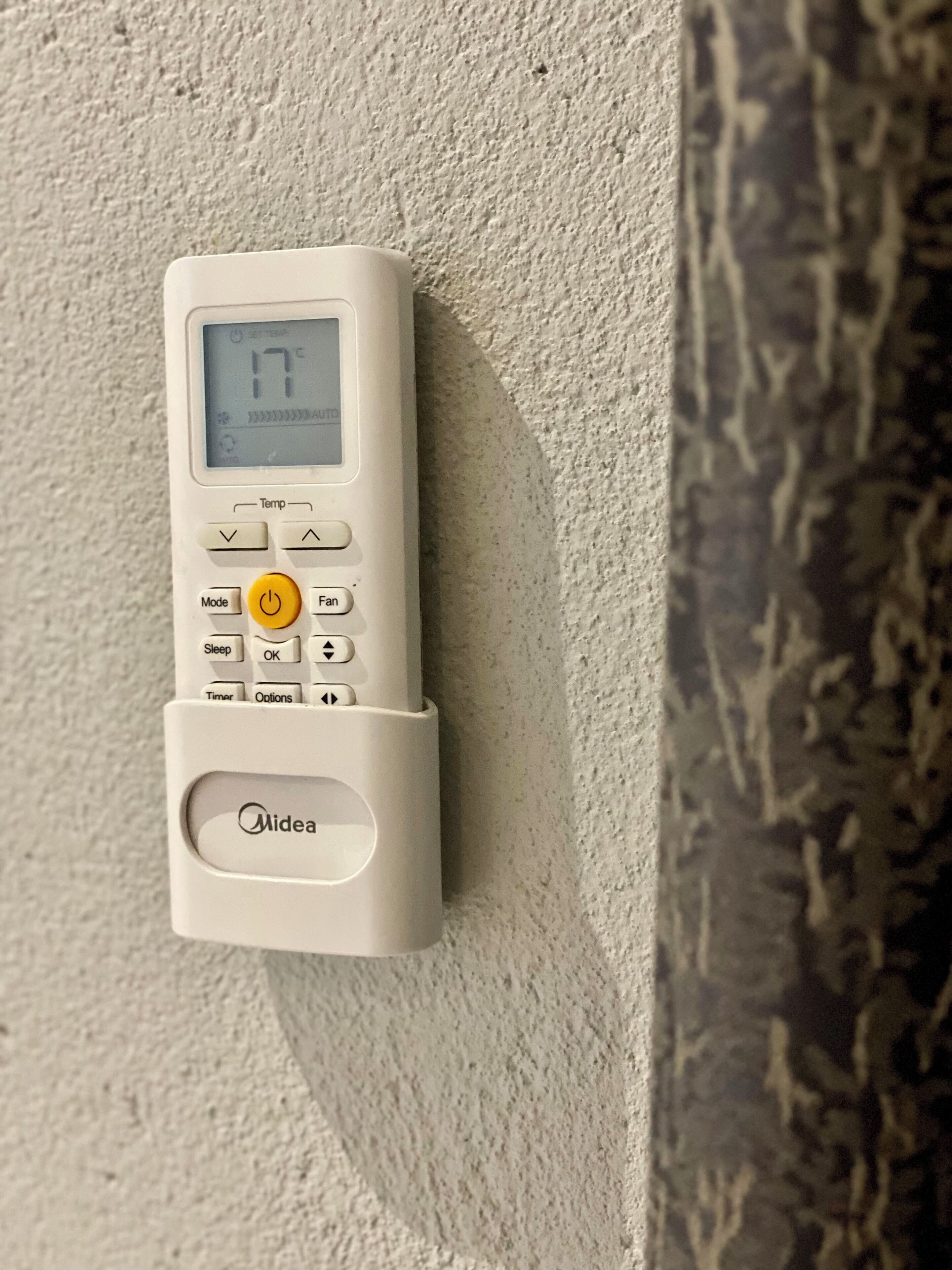 A wall-mounted thermostat with a digital display, control buttons, and a brand name.