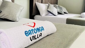A hotel room with two beds, a headboard, and a neatly folded towel with "Batonga Villa" embroidered on it. - BaTonga Villa (Binga)