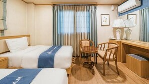 Une chambre d’hôtel avec deux lits, un bureau, une chaise et une fenêtre avec des rideaux.