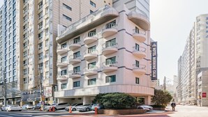 Un hôtel moderne doté de nombreux balcons, d’un spa et d’une enseigne bien visible indiquant « Hôtel Morning Calm ».