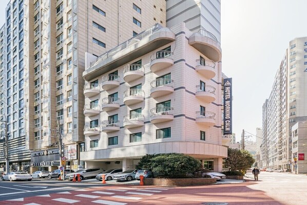 Un hotel moderno con varios balcones, un spa y un cartel visible que dice 'Hotel Morning Calm'.