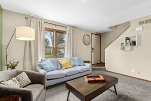 Un salon moderne avec un canapé gris, une table basse en bois et un lampadaire.
