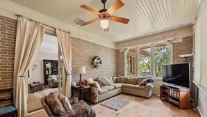 A living room with a sectional sofa, a recliner, a television, and a ceiling fan. - Majestic Hyde Park Historic Home (Austin)
