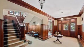 A spacious interior with a wooden staircase, a dining area, and a chandelier. - Majestic Hyde Park Historic Home (Austin)