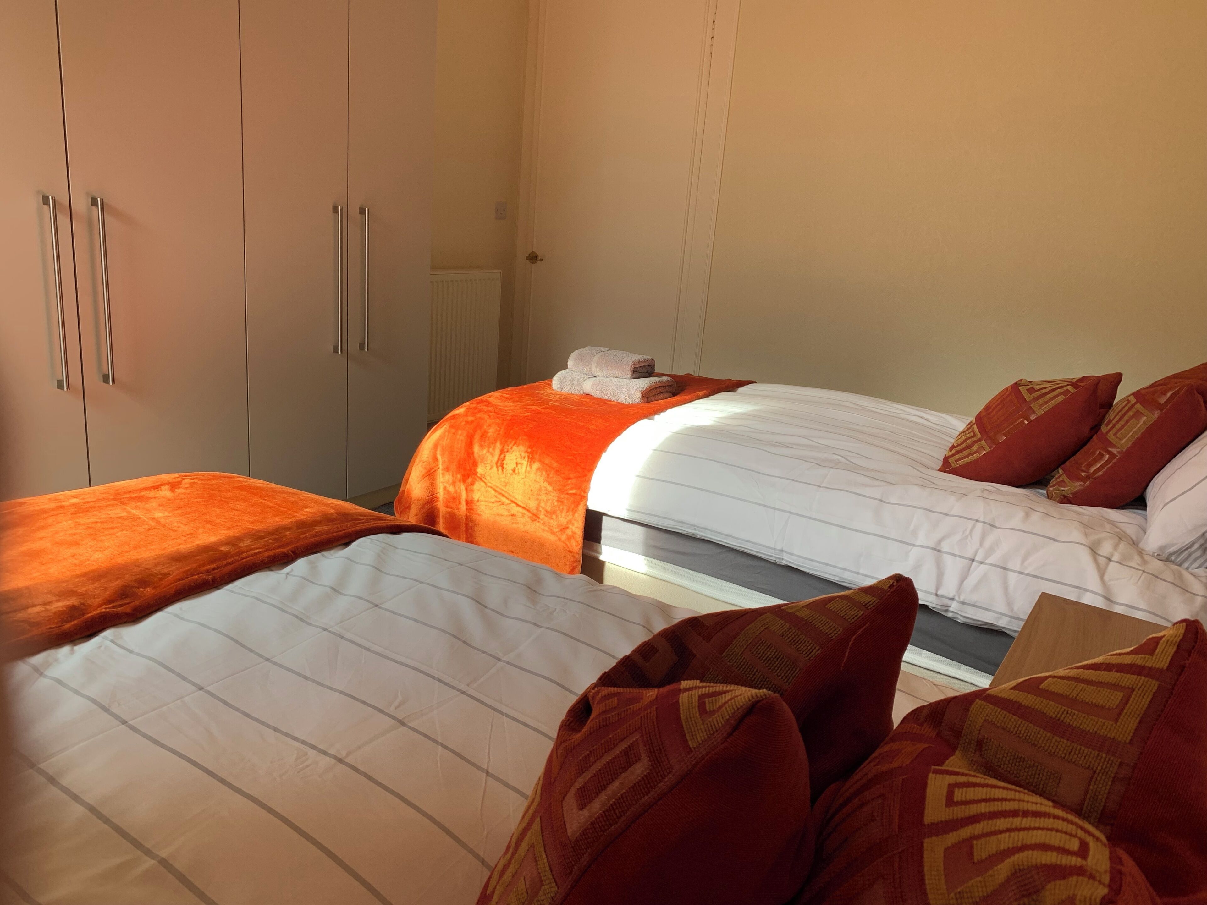 Habitación de hotel con dos camas, cada una con una colcha diferente, y un armario con puertas correderas.