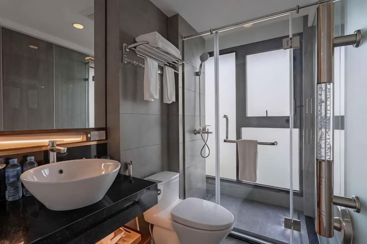 Une salle de bain moderne avec un grand lavabo blanc, des toilettes et une douche à parois de verre.