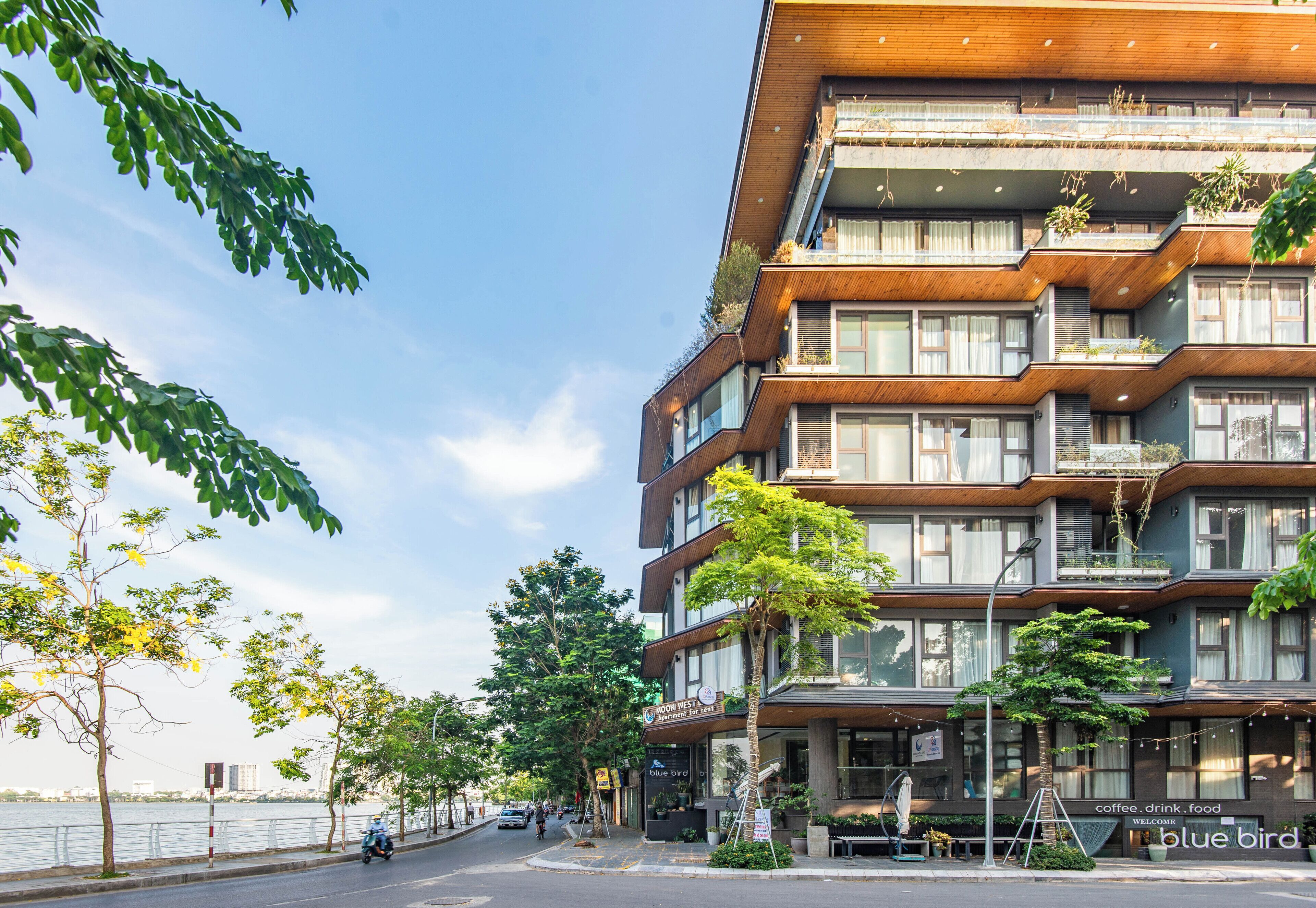 A multi-story building with balconies, a restaurant named 'Blue Bird' at the ground level, and a waterfront view.
