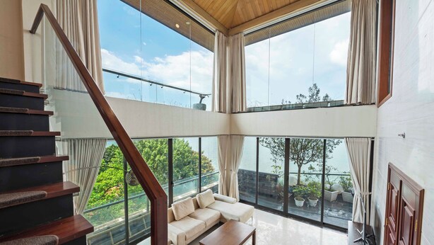 Amplia sala de estar con un ventanal grande, una escalera de madera y un sofá.