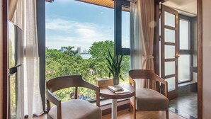 Una habitación con un ventanal grande, dos sillas, una mesita y una planta en maceta.