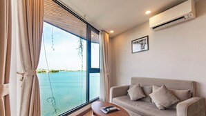Una habitación con un ventanal grande, un sofá, una mesita y un equipo de aire acondicionado.