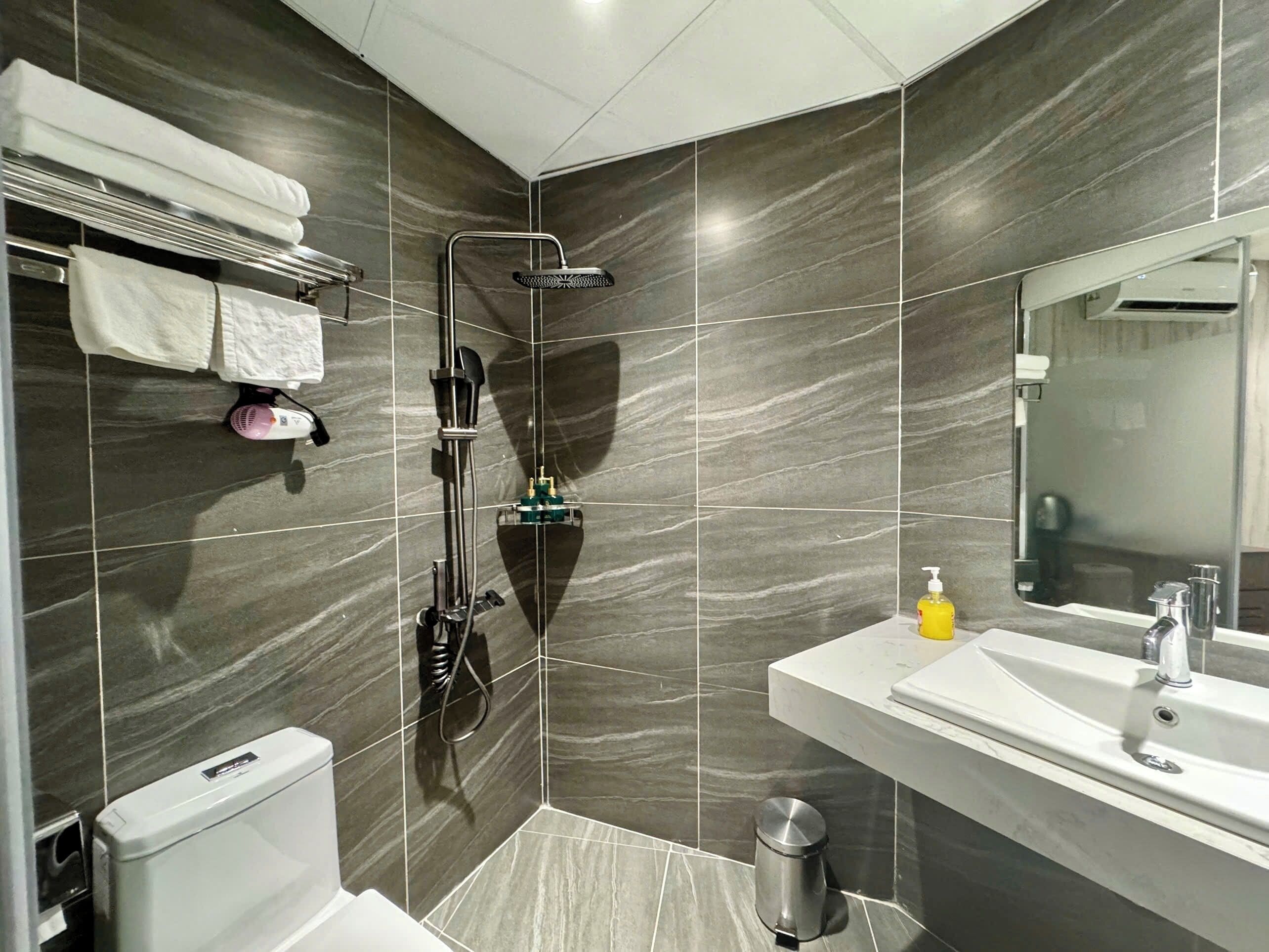 A modern bathroom with a shower, toilet, sink, and a mirror.