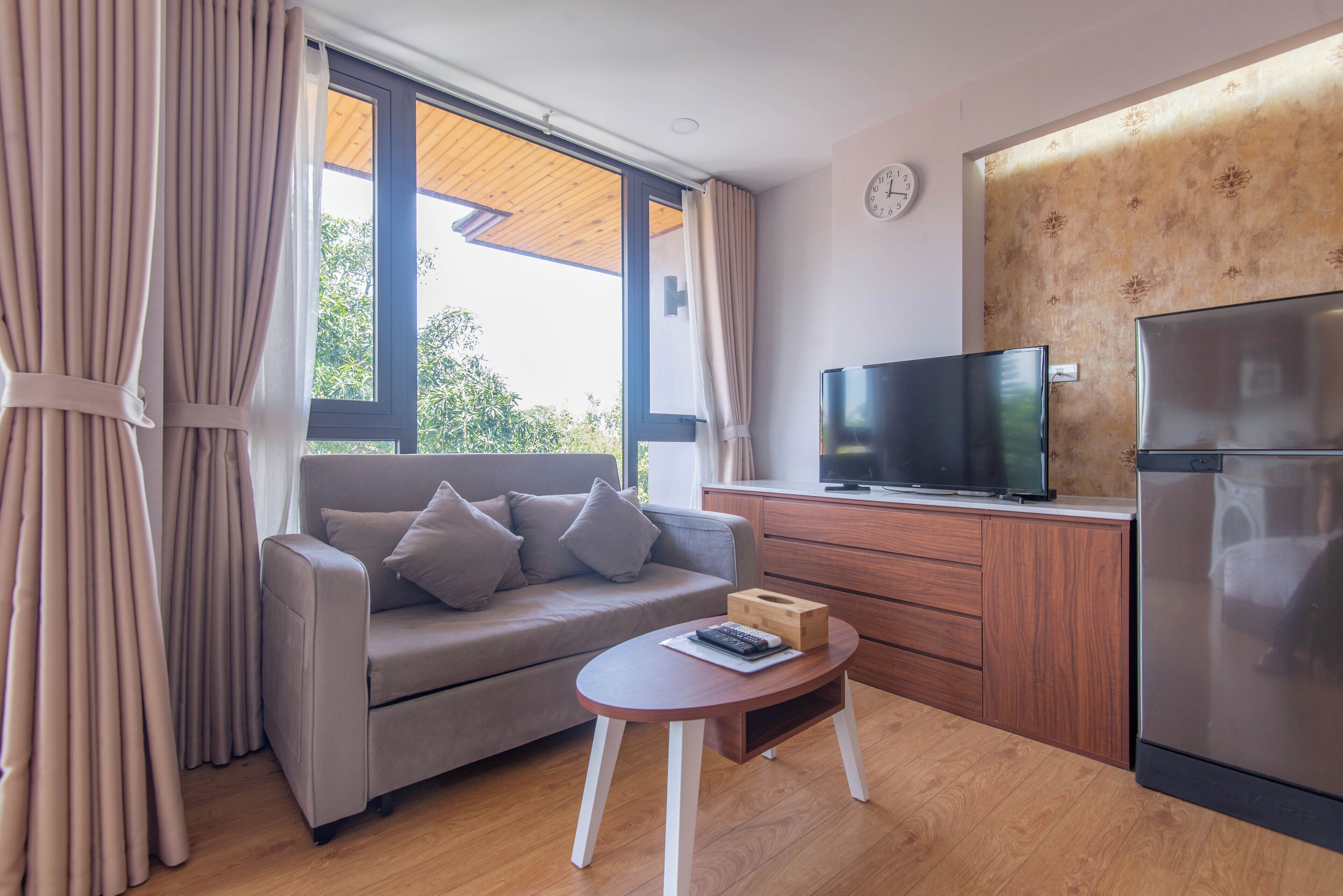 Una sala de estar moderna con sofá, mesa de centro, televisor y refrigerador.