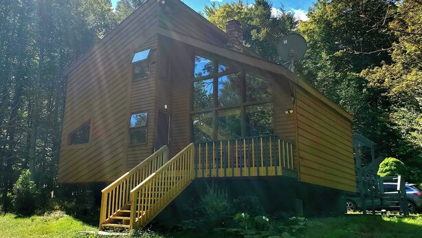 A wooden cabin with a staircase leading to a deck, surrounded by trees. - Shambhala Mountain Retreat: A chalet surrounded by forest. Relax & unwind! (Napanoch)