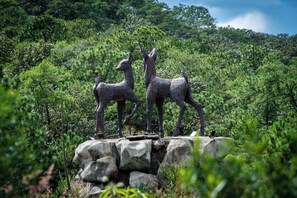 A sculpture of deer on a rocky outcrop surrounded by dense forest.