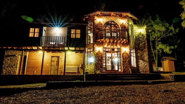 A two-story stone building with a balcony and a wooden door. - Roca Venados (Mascota)