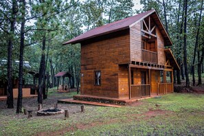 A wooden cabin with a balcony, surrounded by trees.