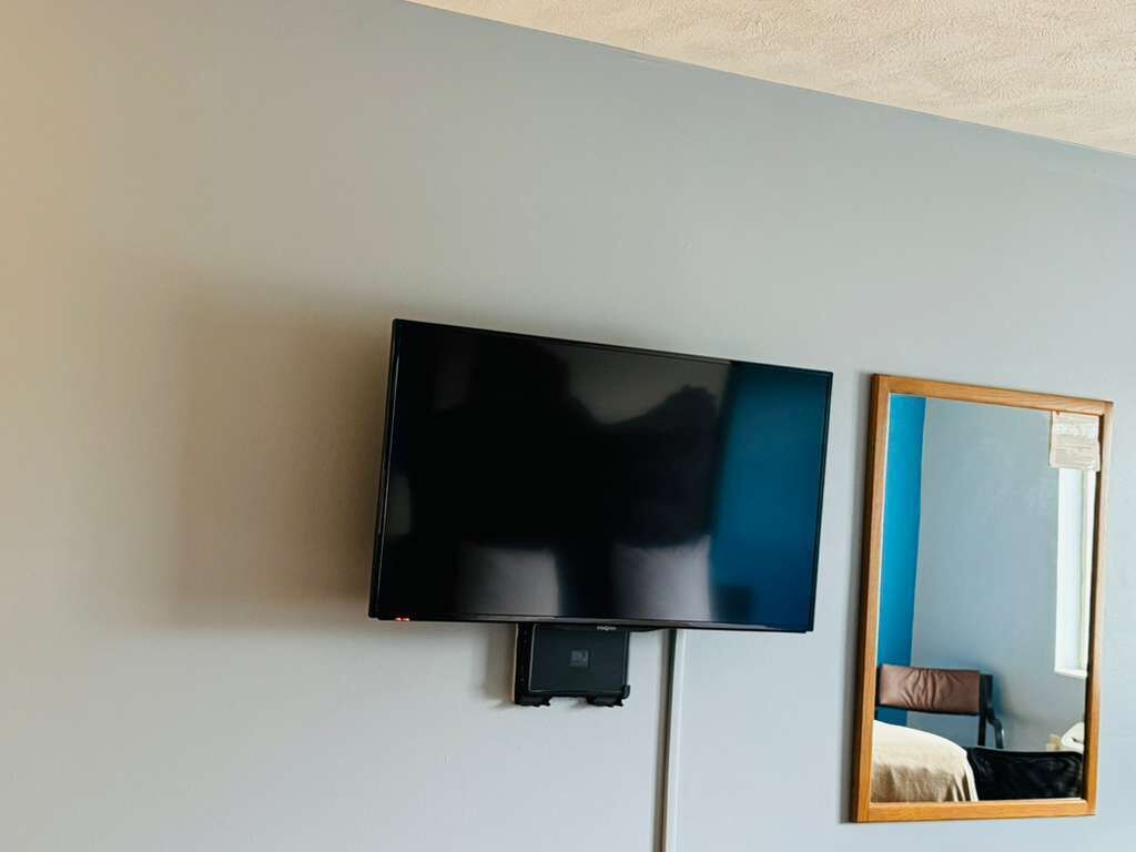 Un téléviseur à écran plat fixé au mur, un miroir et une porte.