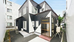 A modern two-story building with a black and white color scheme, a glass entrance, and a sign reading 'THE Beehive I'. - THE BEEHIVE 1 (Sapporo)