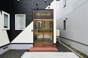 L’entrée d’un immeuble, avec une enseigne indiquant : « THE Beehive I ».