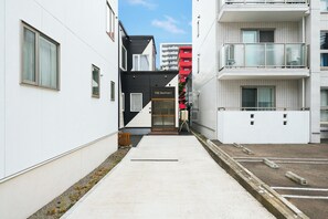 A narrow alleyway between two modern buildings with a clear sky above. - THE BEEHIVE 1 (Sapporo)