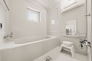 Ein modernes Badezimmer mit einer freistehenden Badewanne, einem kleinen Waschbecken, einem Fenster und einem Spiegel.