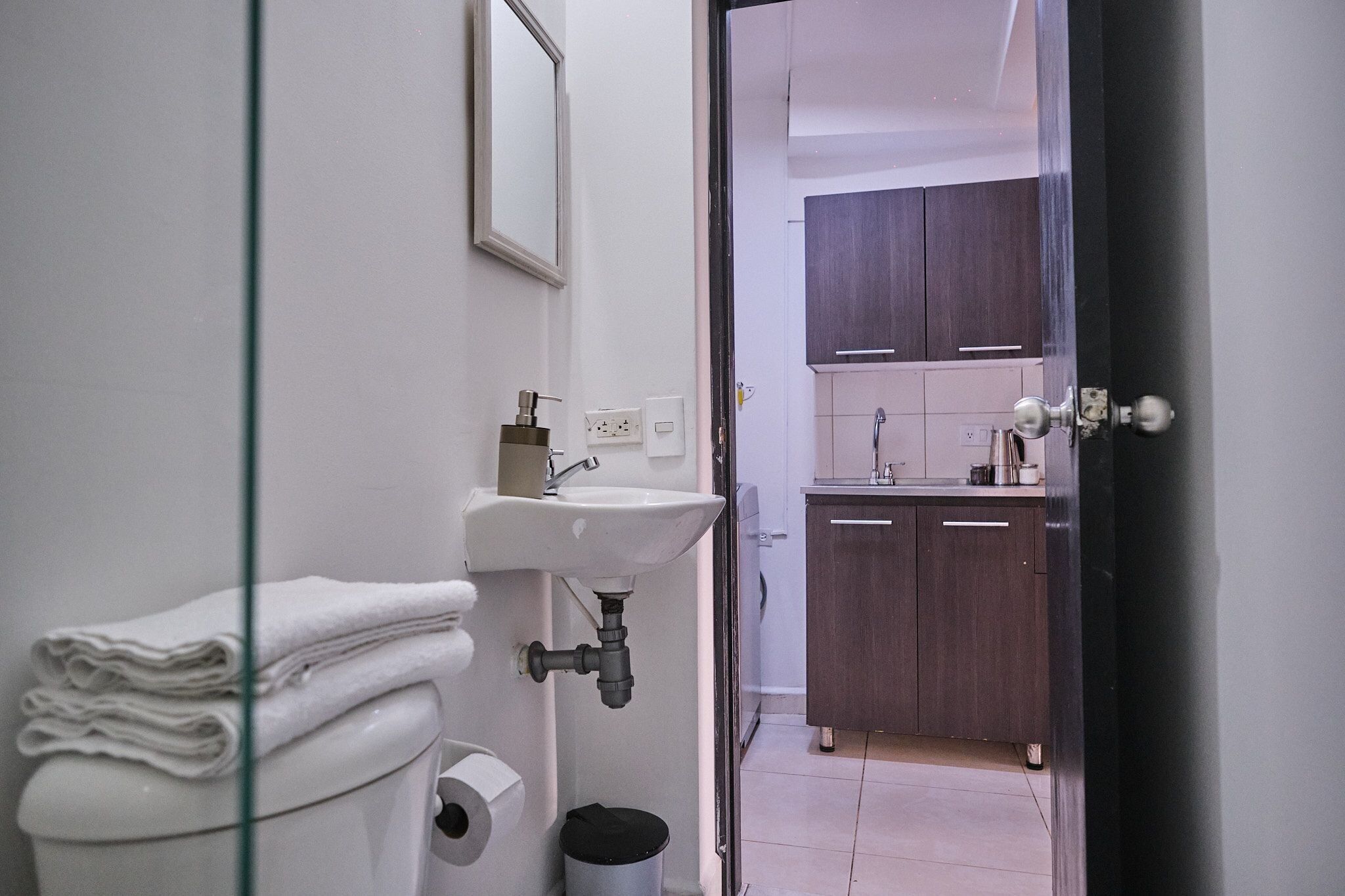 A bathroom with a toilet, sink, and stacked towels.