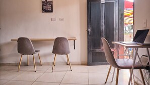 Une pièce avec deux chaises, une table et un ordinateur portable. Il y a une porte avec un numéro et une vue sur l’extérieur.