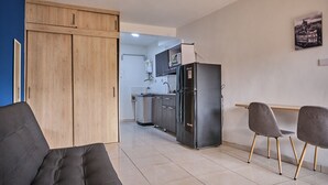 Une cuisine moderne équipée d’un réfrigérateur, d’un four à micro-ondes et de placards. On y trouve également un coin repas avec deux chaises et une table.