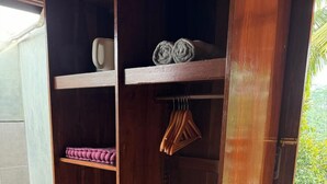 Un armario de madera con estantes y espacio para colgar, situado en una zona con baldosas y vistas al verdor.