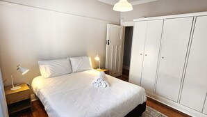 Une chambre à coucher avec un lit, des tables de chevet, une lampe, une armoire et une porte.