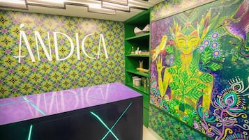 A vibrant room with a colorful wall pattern, a reception desk, and a green shelving unit.