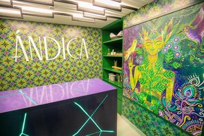 A vibrant room with a colorful wall pattern, a reception desk, and a green shelving unit. - Hotel V1501 Sas (San Juan de Pasto)