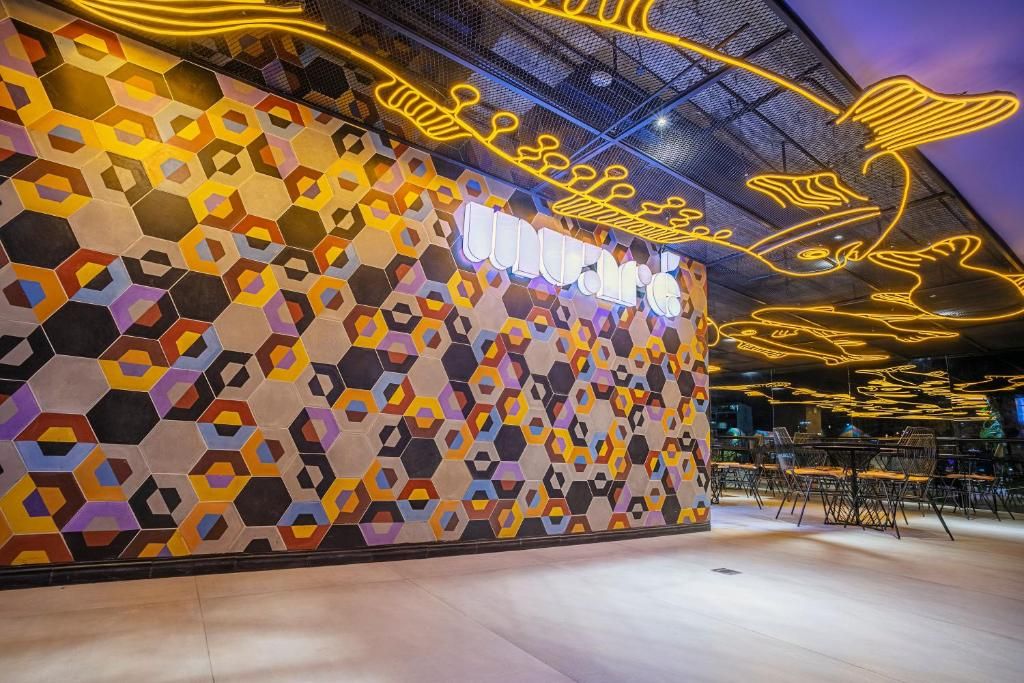Un intérieur moderne avec un mur orné d'un motif géométrique, un panneau lumineux au néon et un espace salon.