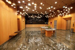 Un vestíbulo espacioso con suelo de mármol, paredes de madera y una mesa central con un jarrón de flores.