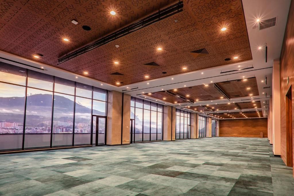 Una amplia sala de conferencias con ventanas grandes, techo decorado y vistas a la ciudad.