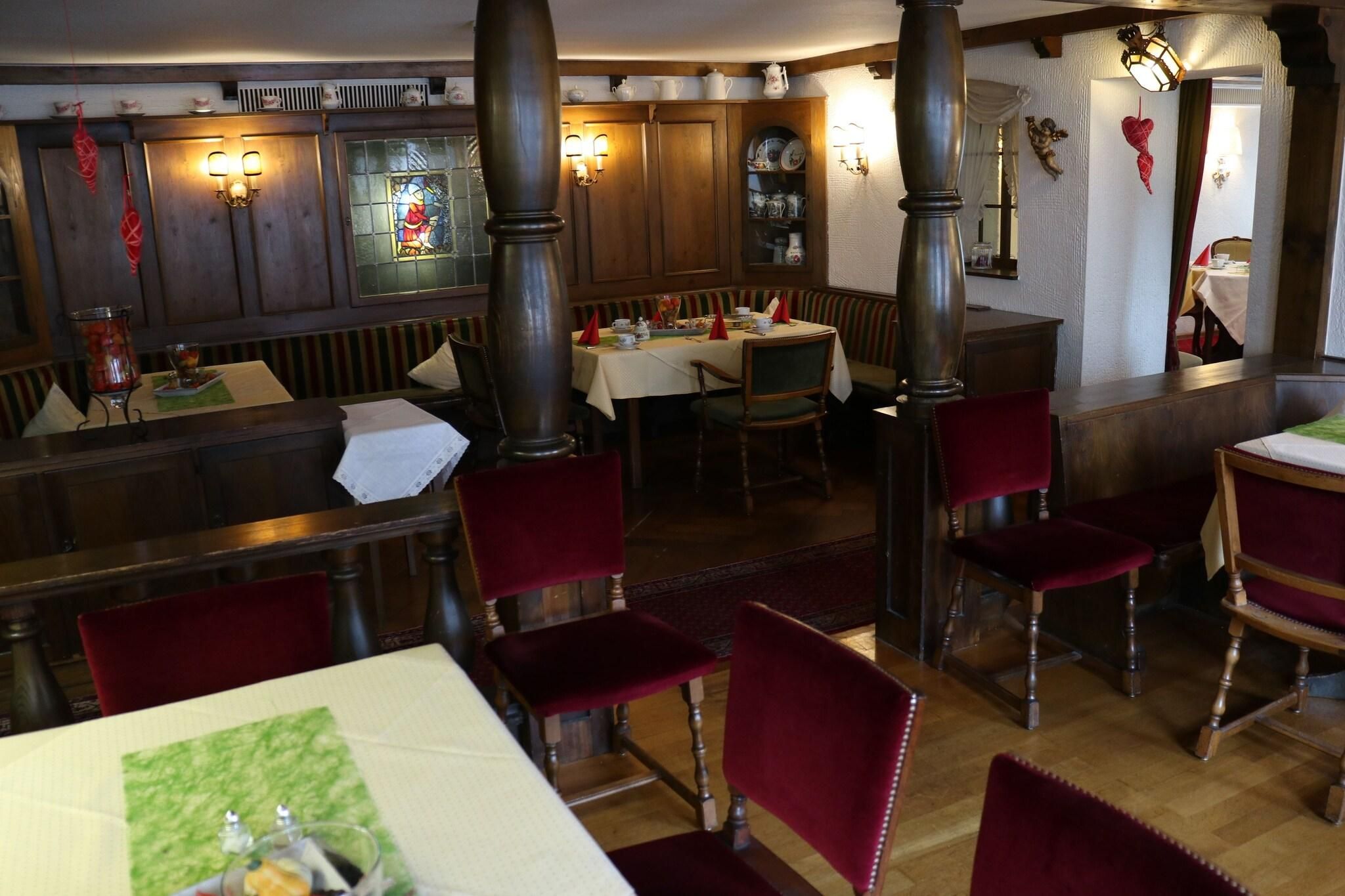 Ein Restaurant mit Holzwänden, roten Samtsesseln und einem Buntglasfenster.