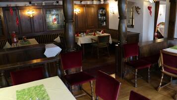 Ein Restaurant mit Holzwänden, roten Samtsesseln und einem Buntglasfenster.