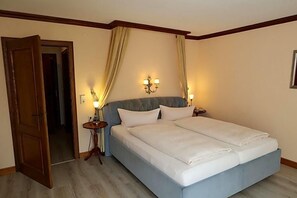 Un lit double avec une tête de lit bleu clair, deux lampes de chevet et un luminaire fixé au mur.