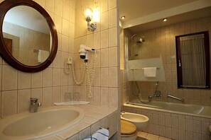 Une salle de bain avec un grand lavabo ovale, un miroir, un sèche-cheveux, une douche et des toilettes.