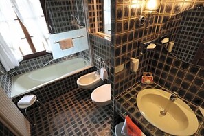 Kylpyhuone, jossa on kylpyamme, kaksi wc:tä, pesuallas ja peili.