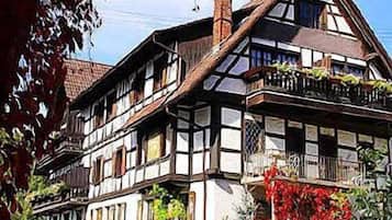 Ein traditionelles Fachwerkhäuschen mit mehreren Stockwerken, großen Fenstern und einem Balkon mit Pflanzen.