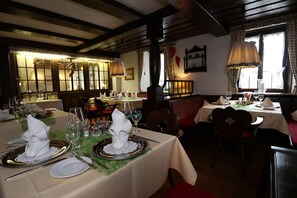 Un restaurant où de nombreuses tables sont dressées pour le service, avec une disposition soignée des assiettes, des verres et des couverts.