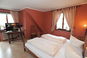 Een kamer met twee bedden, een televisie, een houten tafel en gordijnen.