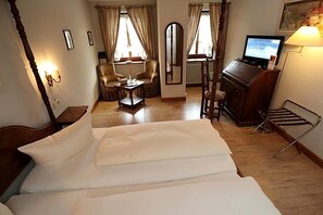 Een hotelkamer met een groot bed, een bureau met stoel, een televisie en een spiegel.