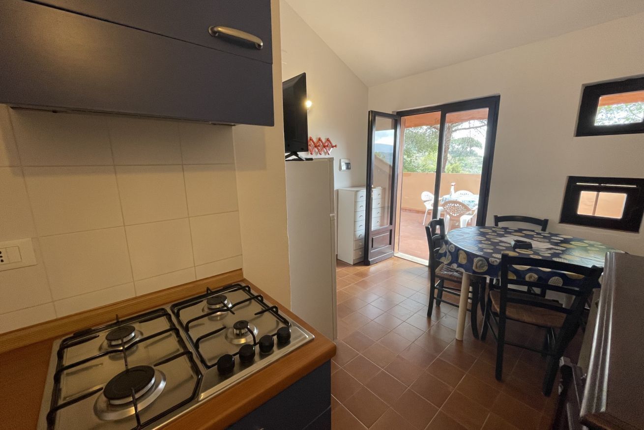 A kitchen with a gas stove, a refrigerator, and a dining area with a table and chairs.