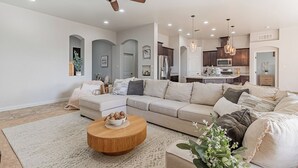 A modern living room with a sectional sofa, a wooden coffee table, and a ceiling fan. - 4BR Modern Farmhouse , Sleeps 10 , Backyard & Theater Room (Yuma)