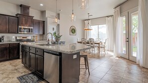 A modern kitchen with dark wood cabinets, stainless steel appliances, and a large island. - 4BR Modern Farmhouse , Sleeps 10 , Backyard & Theater Room (Yuma)