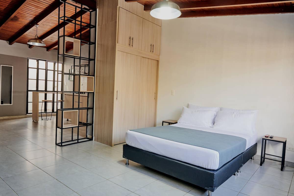 A modern bedroom with a bed, a wooden wardrobe, and a built-in shelving unit.