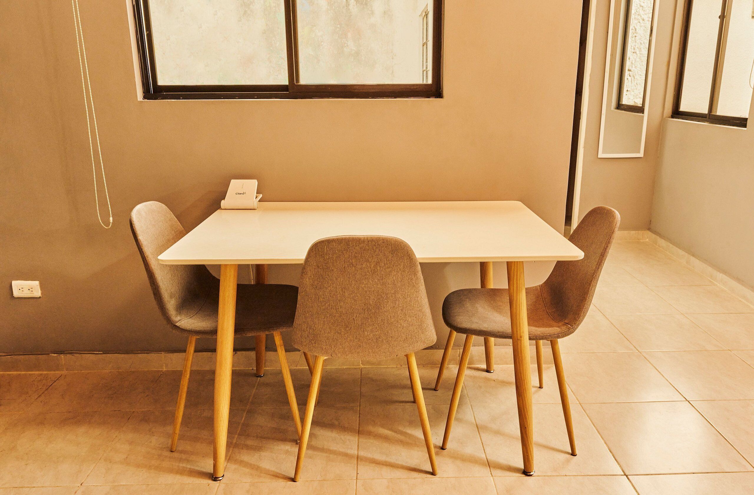 A dining area with a rectangular table, four chairs, and a window providing natural light.